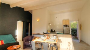 Een moderne woonkamer met een bank, een eettafel gedekt voor twee personen, en een keuken op de achtergrond.