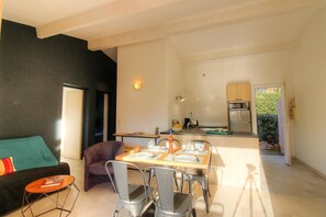 A modern living room with a sofa, a dining table set for two, and a kitchen in the background. - A mini villa with swimming pool less than 5 kilometers from the beach (PORTO VECCHIO)