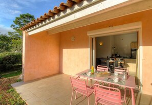 A patio with a table and chairs, a kitchen visible through an open door, and a tiled roof. - A mini villa with swimming pool less than 5 kilometers from the beach (PORTO VECCHIO)
