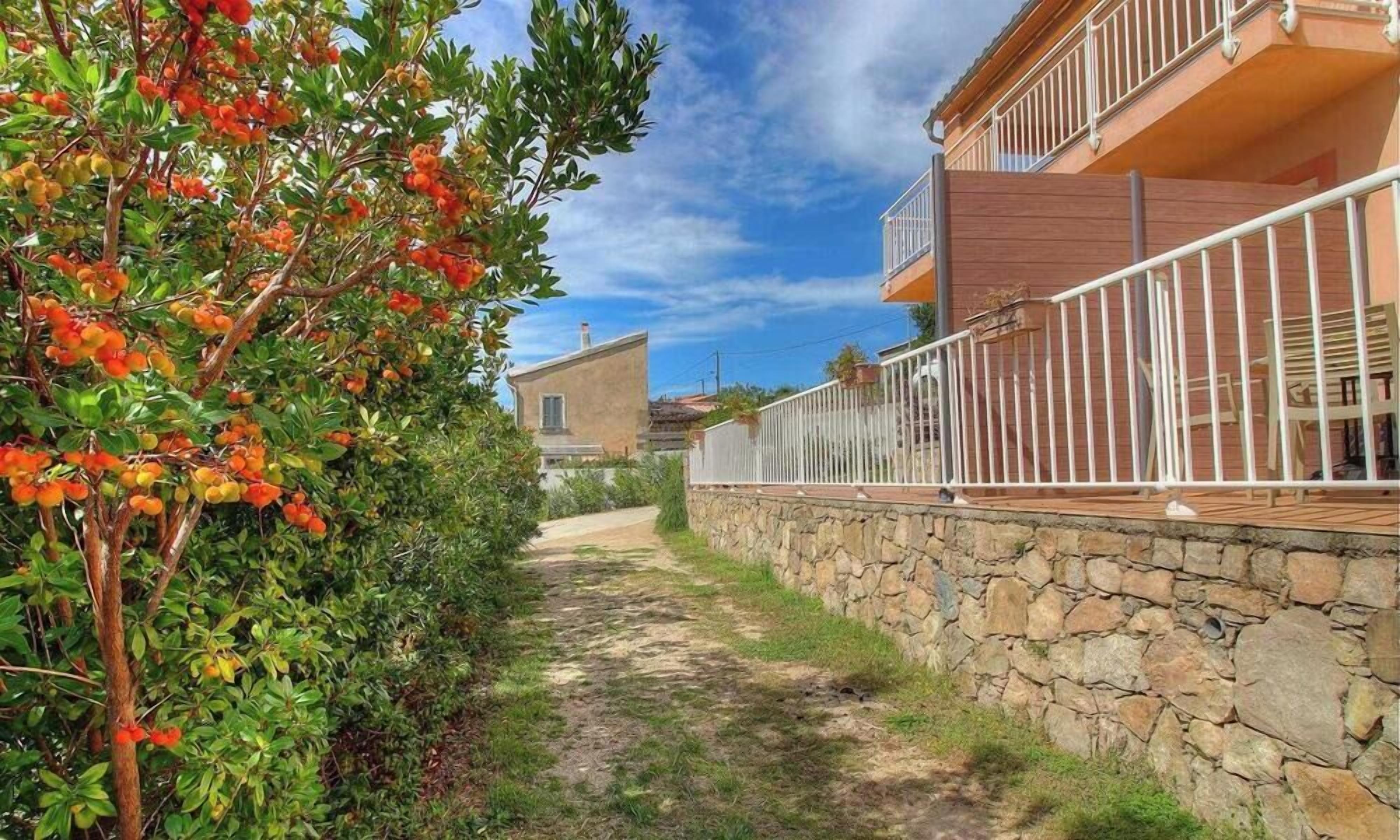A narrow pathway leading to a stone wall with a balcony.