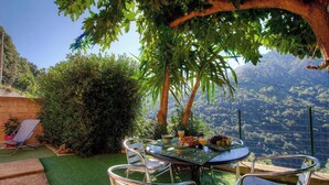 Une table à manger avec des chaises, entourée de verdure et offrant une vue pittoresque.