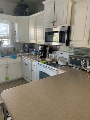 A kitchen with white cabinets, a stainless steel microwave, a dishwasher, and a toaster oven.
