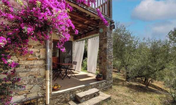 A stone building with a balcony, a table, chairs, and a potted plant. - Alivetu - CERVIONE - Gîte (CERVIONE)