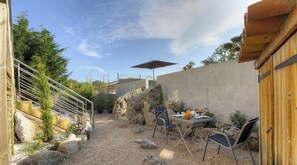 Eine Terrassenfläche mit Esstisch, der für ein Frühstück gedeckt ist, Sitzgelegenheiten im Freien und einer Treppe zu einer oberen Ebene.
