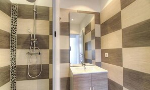 Ein Badezimmer mit Dusche, Waschbecken und Spiegel.