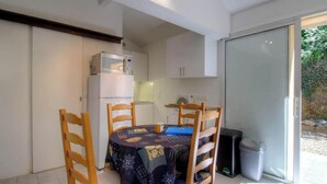 Cocina compacta con refrigerador, microondas y una mesa con sillas.