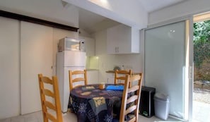 A compact kitchen with a refrigerator, microwave, and a dining table with chairs. - Tilleul 2 - COSTA - Gîte (COSTA)