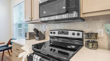 Una cocina con un microondas de acero inoxidable, una estufa y un especiero.