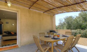 Eine Terrass mit Tisch, Stühlen, einem Grill und einer Couch im Inneren eines Gebäudes.