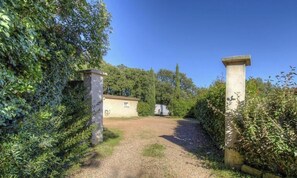 Ein Kiesweg führt zu einem Gebäude mit einem kleinen Garten und einem abgestellten Transporter.