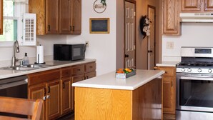 A kitchen with wooden cabinets, a microwave, a stove, and a sink. - Large Family Home with Backyard Oasis & Fire Pit (Florence)