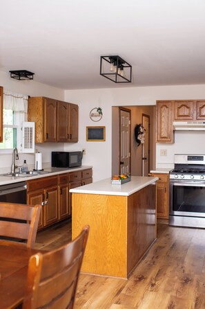 Une cuisine avec des meubles de rangement en bois, un four à micro-ondes, une cuisinière et un évier.