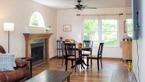 A living room with a fireplace, dining table, chairs, a sofa, and a ceiling fan. - Large Family Home with Backyard Oasis & Fire Pit (Florence)