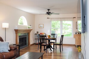 Un salon avec une cheminée, une table à manger, des chaises, un canapé et un ventilateur de plafond.