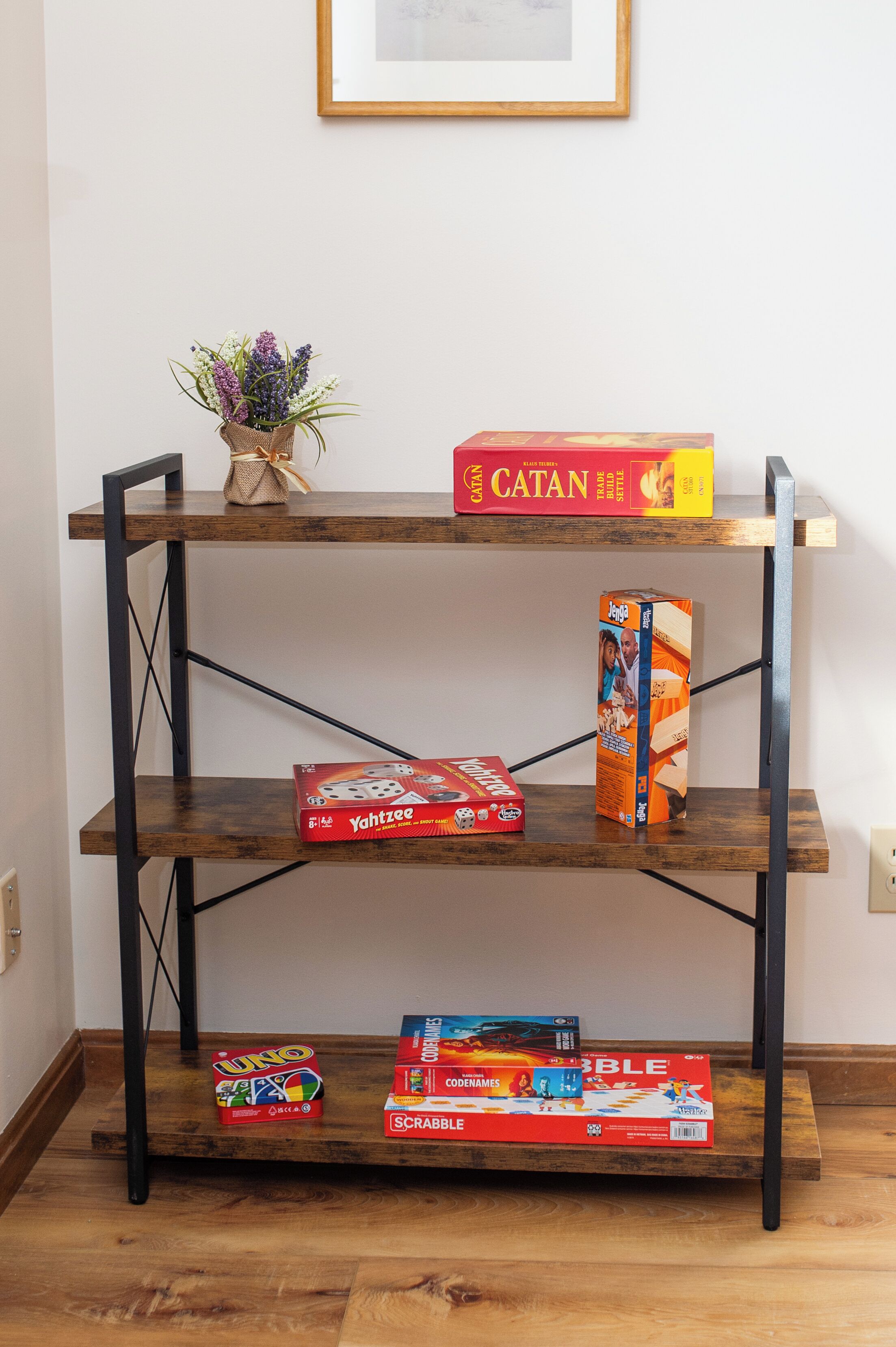 Uno scaffale di legno con giochi da tavolo e una piccola pianta.