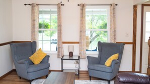A room with two armchairs, a small table, and a window with curtains. - Large Family Home with Backyard Oasis & Fire Pit (Florence)
