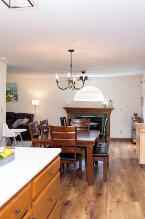 A dining area with a wooden table and chairs, a chandelier, and a fireplace.