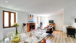 Ein modernes Wohnzimmer mit Kamin, einem Esstisch für sechs Personen und einer Couch.