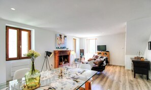 A modern living room with a fireplace, a dining table set for six, and a sofa. - Casa Di Ghjulia e Anto (BALOGNA)