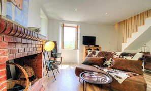 A living room with a brick fireplace, a sofa, a TV, and a staircase. - Casa Di Ghjulia e Anto (BALOGNA)