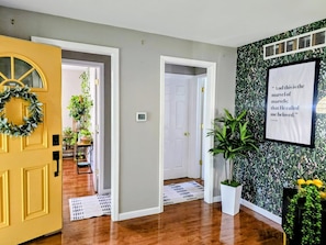 A hallway with a yellow door, a framed quote on the wall, and a plant in a white pot. - Cozy Perrysburg Retreat..Your Tranquil Downtown Escape (Perrysburg)