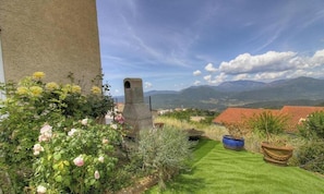 A balcony with a view of mountains, a stone chimney, and potted plants. - Bleuet - SARTENE - Gîte (SARTENE)