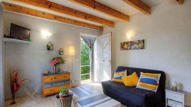 A living room with a sofa, a TV, a wooden dresser, and a door leading outside. - The holm oaks - CONCA (CONCA)