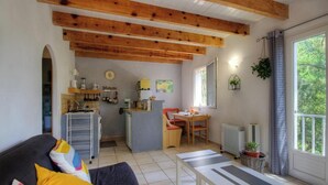 A compact living space with a kitchenette, a dining area, and a large window providing natural light. - The holm oaks - CONCA (CONCA)