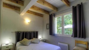 A bedroom with a bed, two bedside lamps, a window with curtains, and a wooden ceiling. - The holm oaks - CONCA (CONCA)