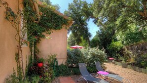 A garden with a pergola, two lounge chairs, and a red umbrella. - Les chênes verts 2 - CONCA (CONCA)