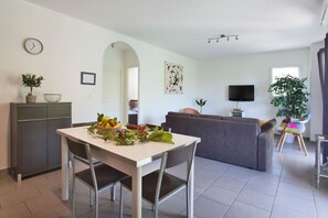 Ein modernes Wohnzimmer mit Essbereich, Sofa, Fernseher und Pflanzen.