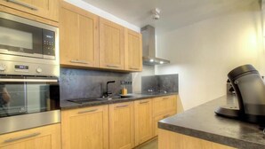 A modern kitchen with wooden cabinets, stainless steel appliances, and a coffee maker. - Cuccia - CORSCIA - Guest house (CORSCIA)