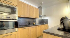 A modern kitchen with wooden cabinets, stainless steel appliances, and a coffee maker. - Cuccia - CORSCIA - Guest house (CORSCIA)