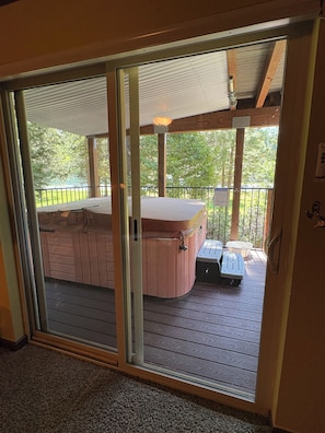 A hot tub on a wooden deck with a glass door leading to a covered area. - Largest Townhome in Leland Meadows, Plus a Hot Tub! (Pinecrest)