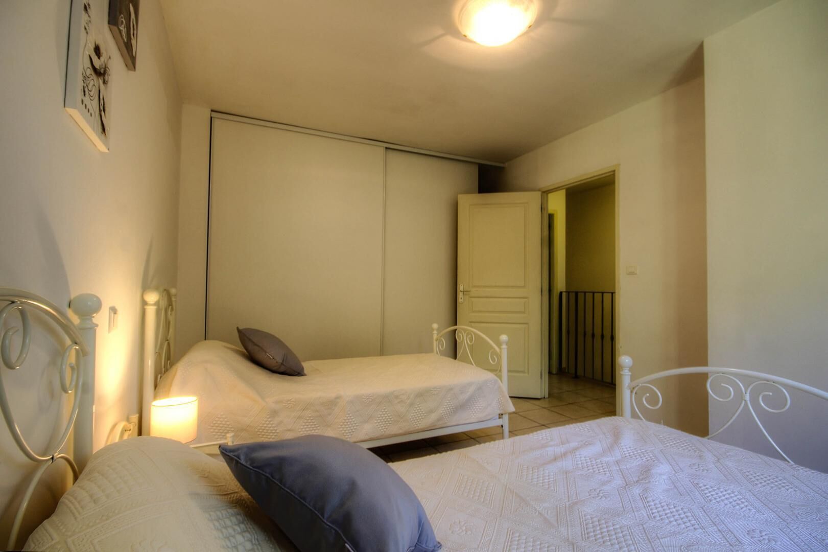 Un dormitorio con dos camas individuales, una puerta blanca y un pequeño balcón.