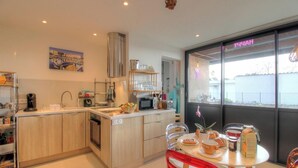 Una cocina moderna con armarios de madera, una campana extractora de acero inoxidable y un comedor con mesa para dos.