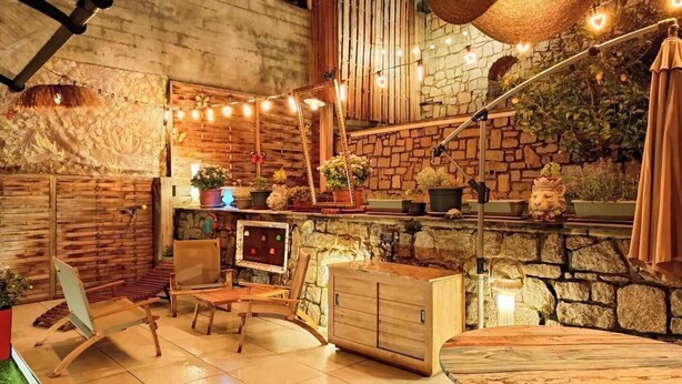Un interior acogedor y rústico con pared de piedra, muebles de madera e iluminación con guirnaldas.