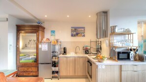 Cocina compacta con refrigerador, microondas, lavamanos y un pequeño comedor.