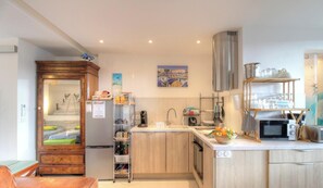 Eine kleine Küche mit Kühlschrank, Mikrowelle, Spüle und einem Essbereich.