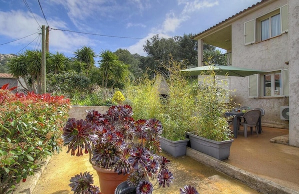 A patio with potted plants, a table, and chairs under a green umbrella. - Antony - SOTTA - Gîte (SOTTA)
