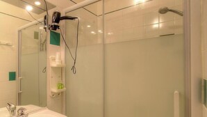Ein modernes Badezimmer mit Duschkabine aus Glas, Waschbecken mit Spiegel und einem an der Wand montierten Fön.