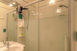 A modern bathroom with a glass shower enclosure, a sink with a mirror, and a hairdryer mounted on the wall. - Anne-Lise - AVAPESSA (AVAPESSA)