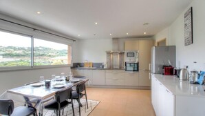 A modern kitchen with a dining area, large windows, and a view of the countryside. - 2Calm - VIGGIANELLO - Gîte (VIGGIANELLO)