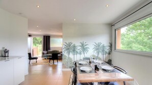 A modern dining area with a table set for four, a kitchen area, and a view of greenery outside. - 2Calm - VIGGIANELLO - Gîte (VIGGIANELLO)