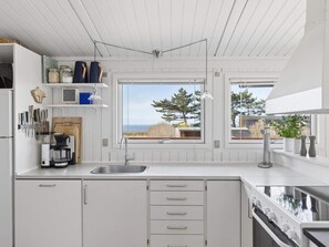 A modern kitchen with a large window, built-in cabinets, and a coffee maker. - 4 Star Holiday Home in Kalundborg (Kalundborg)