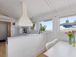 A modern kitchen with a white countertop, a hanging light fixture, and a view of the outdoors through a window. - 4 Star Holiday Home in Kalundborg (Kalundborg)