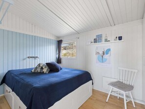 A bedroom with a bed, a chair, a window, and a wall with a poster. - 4 Star Holiday Home in Kalundborg (Kalundborg)