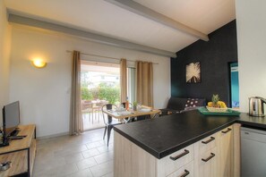 Eine moderne Küche mit Essbereich, einem Flachbildfernseher und Blick ins Freie.
