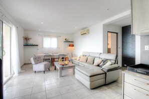 Ein modernes Wohnzimmer mit Sofa, Esstisch, Stühlen und Küchenzeile.