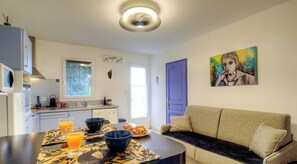 Una cuina moderna amb zona de menjador, un sofà i un quadre a la paret.